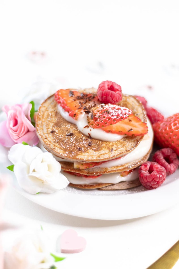 vanilla raspberry glutenfree pancakes topped with cashew yoghurt and strawberries