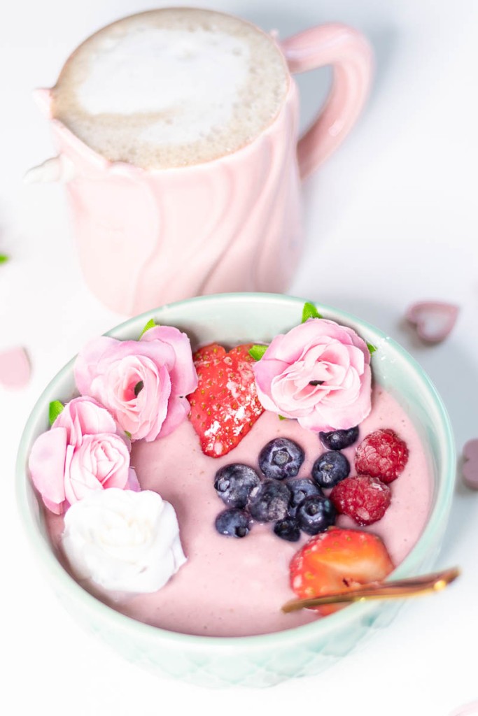 vegan pink smoothie bowl decorated with roses and fresh berries